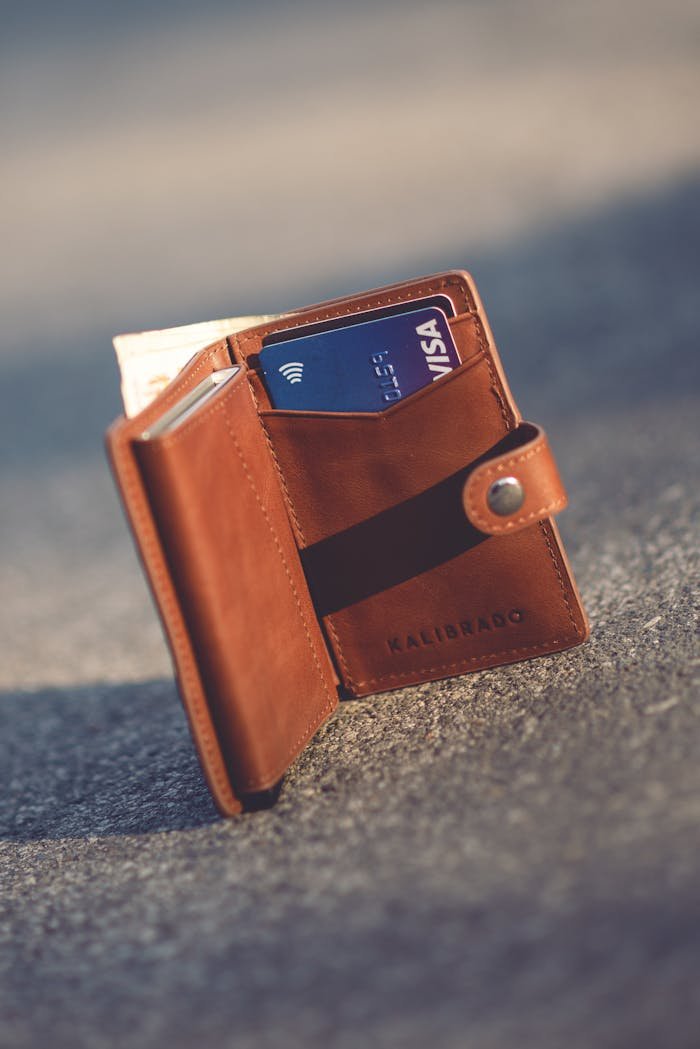 Home A stylish leather wallet with bank cards set on pavement, highlighting luxury and everyday use.